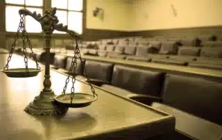 Empty courtroom interior with justice scales resting on a table, representing legal proceedings related to a Colorado DMV express consent hearing. Image symbolizes preparation steps, due process, and the formal setting where license suspension cases are reviewed and decided