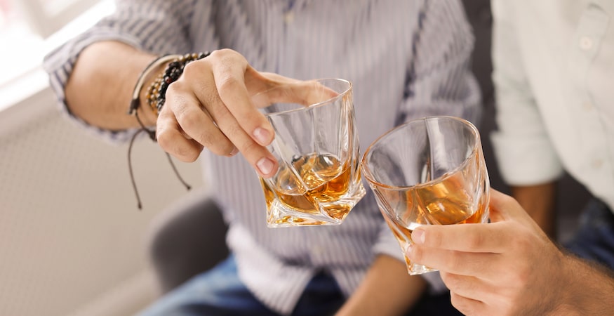Does Alcohol Affect Men and Women Differently Two people clinking glasses of whiskey