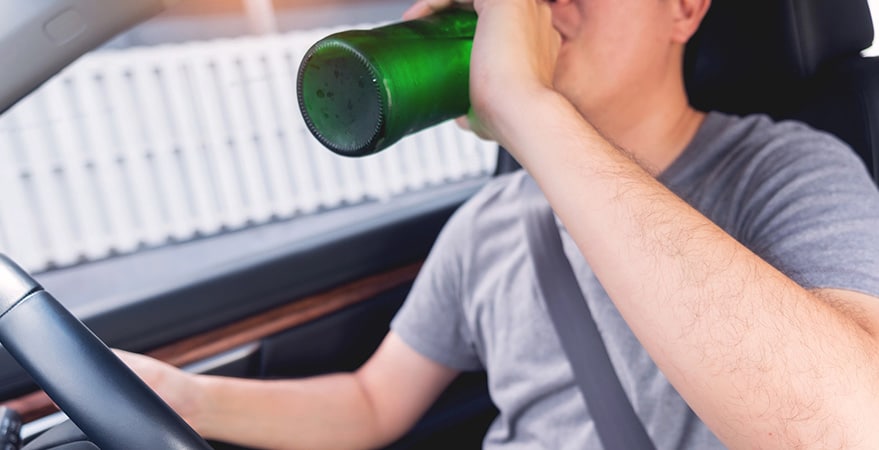 Person drinking from bottle while driving car.