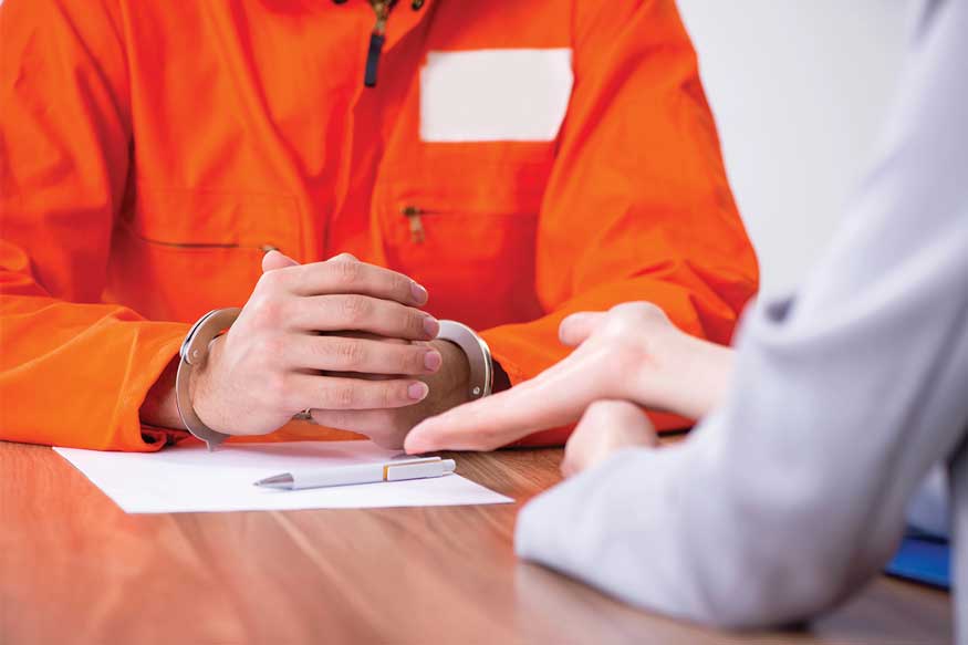 Inmate in handcuffs at legal consultation table. - Plea Bargains in Colorado DUI Cases