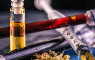 THC testing technology in 2026 examining reliability, impairment detection windows, and court acceptance, shown with cannabis oil and syringes on a table representing modern drug testing and analysis methods.